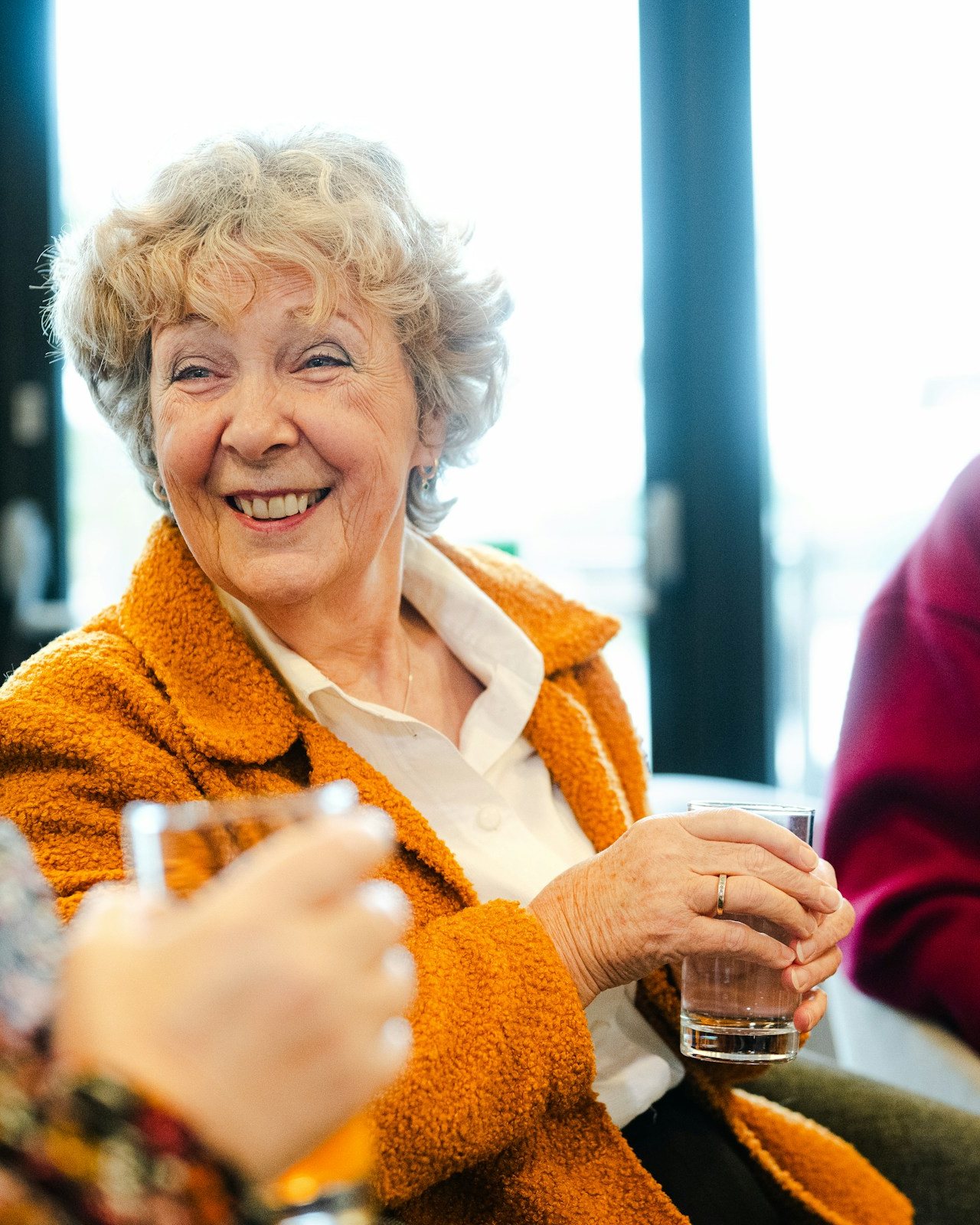 An older woman laughing during a conversation with friends