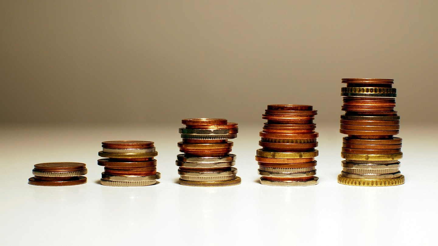Five stacks of coins, each taller than the one before, on a white table