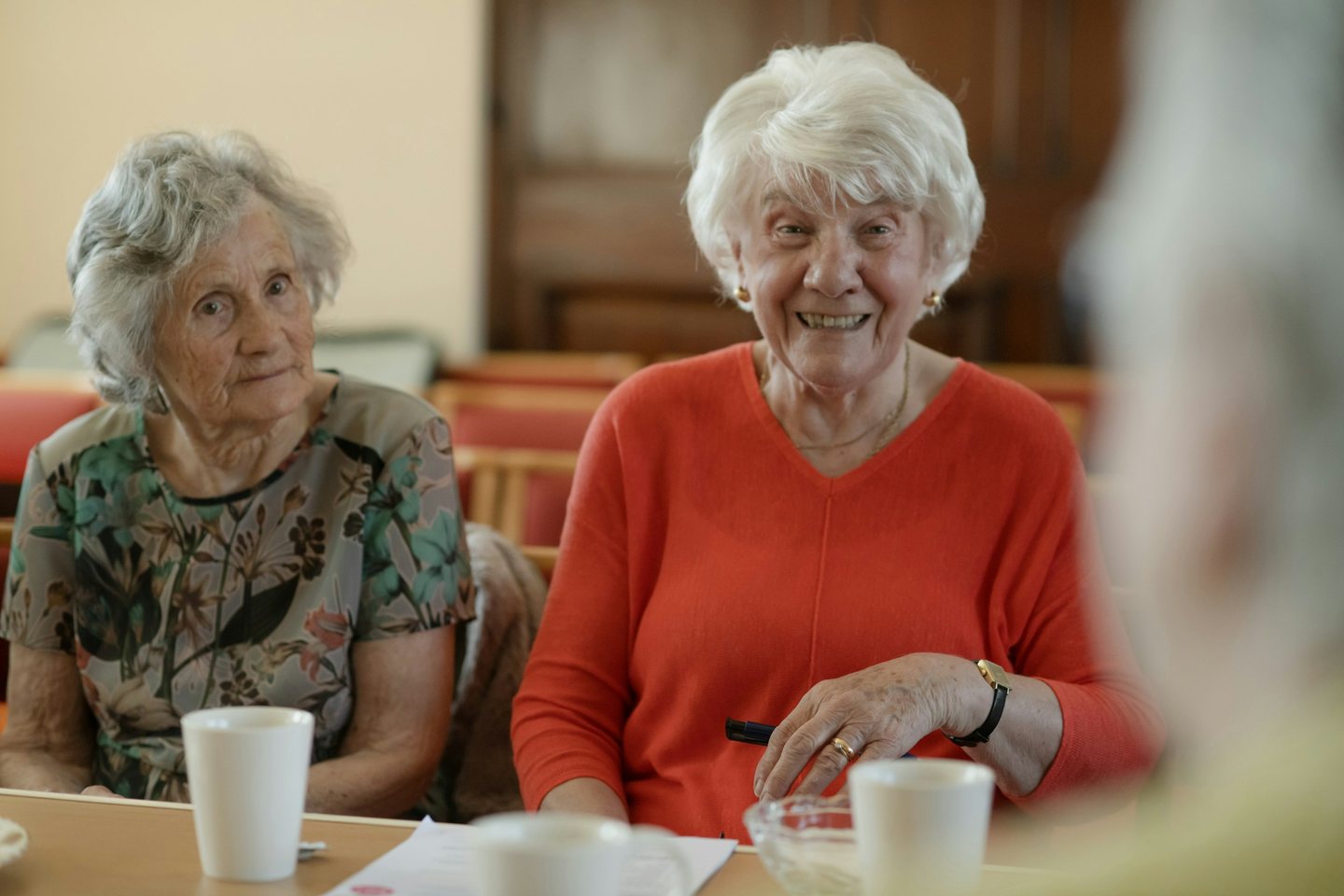 Two older women laughing together at a table