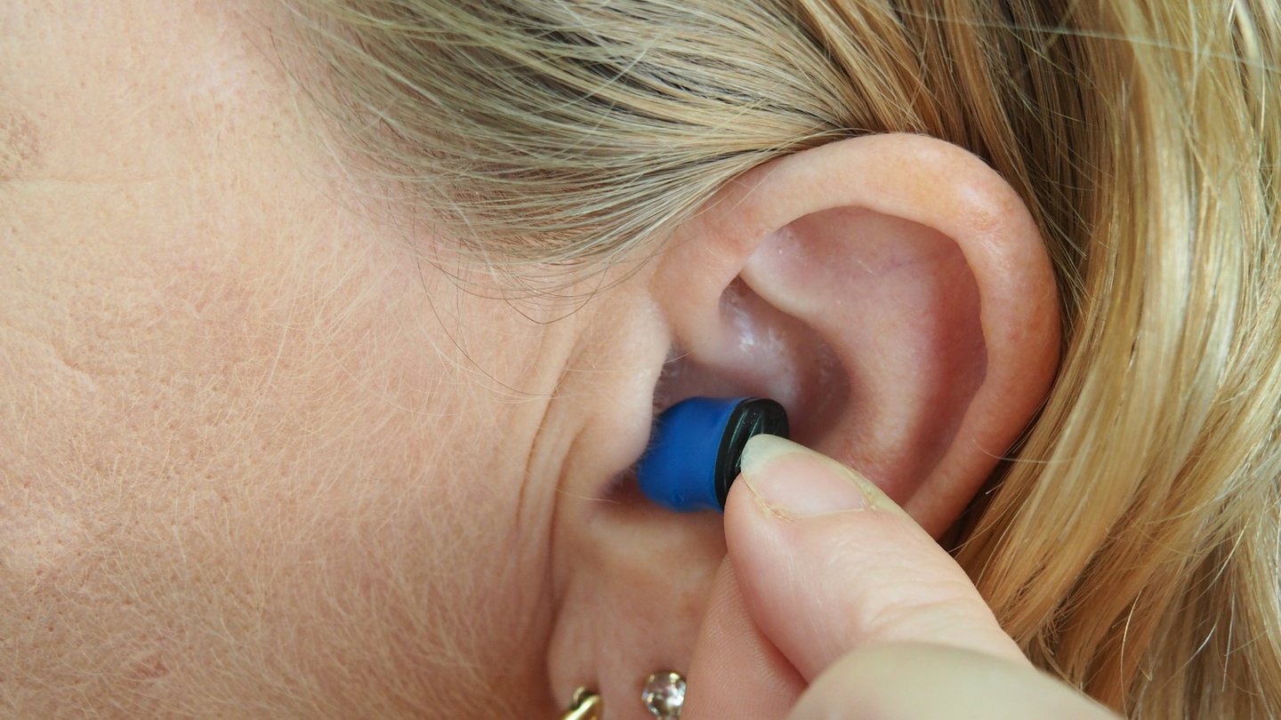 An in-ear hearing device being placed in a woman's ear