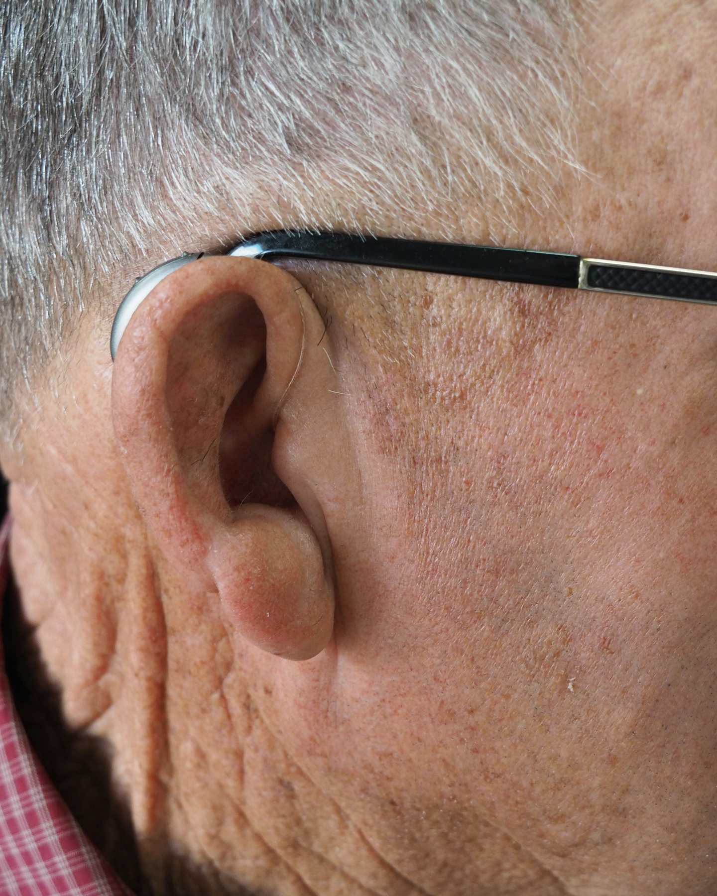 An older man's ear beside the arm of his glasses