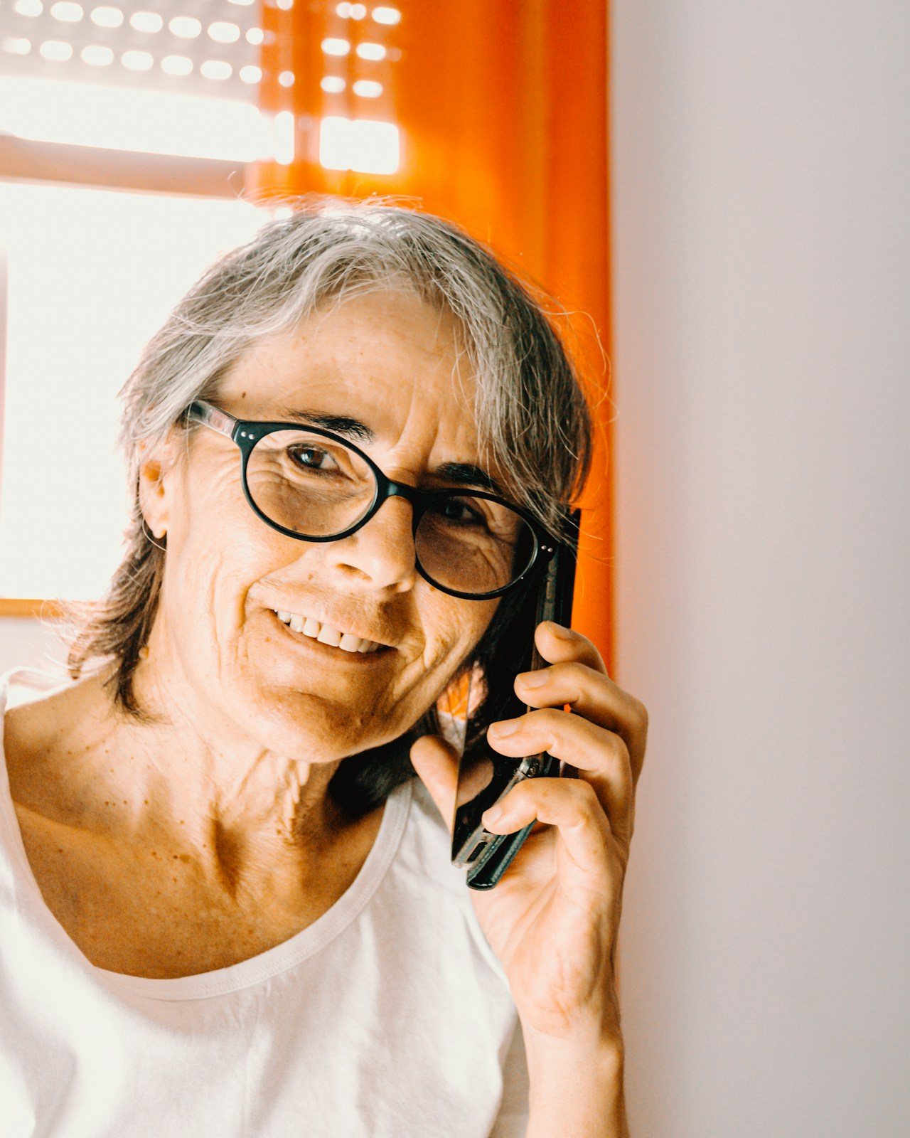 An older woman smiling while she talks on the phone